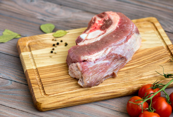 Fresh meat on the wooden table with spices and tomatoes