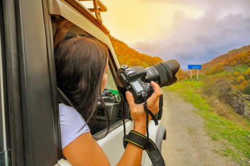 photographer looks out with the camera of the moving car, in search of a good shot
