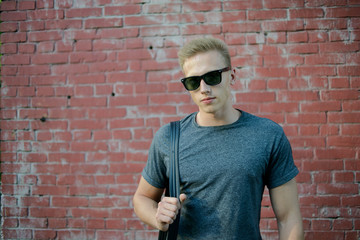Obraz premium A young guy in glasses the brick wall