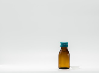 Cough syrup in amber bottle with blank label and teaspoon on white background
