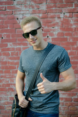 A young guy in glasses the brick wall