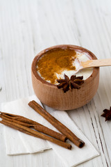 White substance in wooden cup with cinnamon and spices. For hair, face, spa.