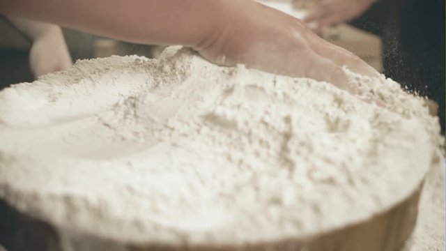 Men's hand mixes flour in a wooden dish - closeup