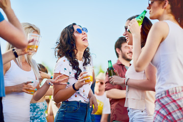 Group of people at outdoor party chatting, drinking and having good time