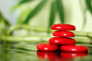 des pierres rouges disposé en mode de vie zen sur sol brillant et arrière plan de feuilled et bambou 