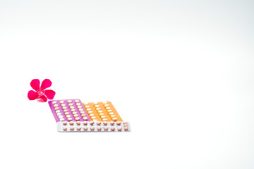 Contraceptive pills with pink flower on white background