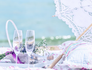 Picnic on the beach. Openwork umbrella, pillow, glasses, in the background a beautiful sea view.
