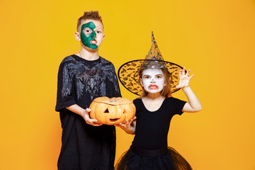 Kids Boy and Girl in Different Halloween Costumes Growling and Frighten camera with Pumpkin...