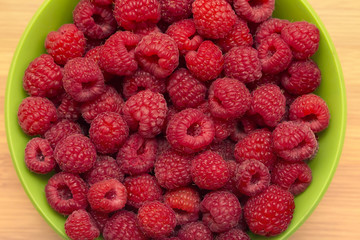Fresh juicy raspberries in a bowl, delicious colorful summer background