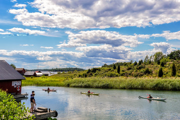 Fishing boys are watching kayaks coming in to Harstena, an island in the gryt archipelago of the Baltic Sea, Sweden