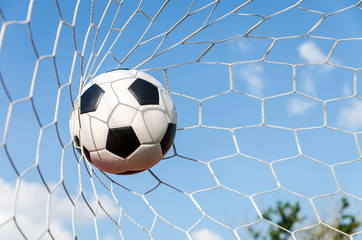 Fototapeta premium Soccer football in Goal net with the sky field.