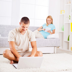 Beautiful couple at home using gadgets.