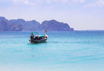  longtail boat sailing on the tropical andaman sea with small limestone island background at krabi thailand.