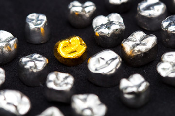 Dental  gold and metal tooth crowns on dark black surface.