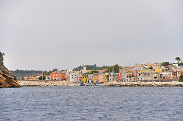 Fototapeta na wymiar Bright houses the masts of the yachts in Marina on the island of Procida