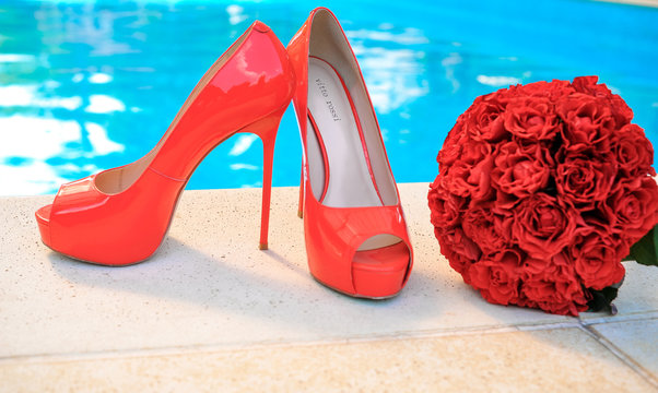 Stylish red shoes for walking close-up with a red bouquet
