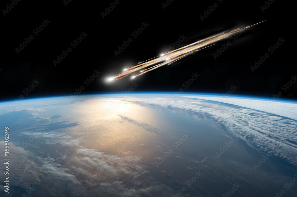 Wall mural a meteor streaks towards a collision with earth as it breaks up over the ocean. clouds cover an ocea
