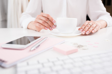 cropped shot of businesswoman with perfect manicure drinking coffee at workplace