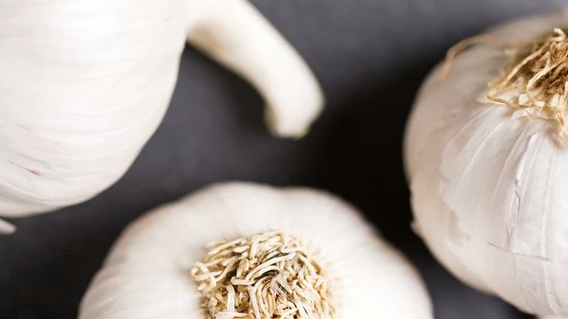 Slowly panning over fresh ripe garlic bulbs on a slate surface