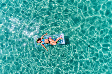 aerial view  of a beautiful young woman in bikini on a matress in the sea