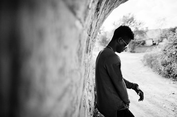 Handsome young african american guy in casual clothing and sunglasses posing and walking in the tunnel.