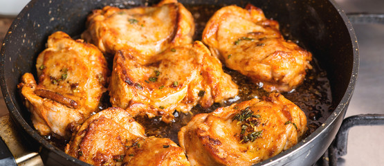 Fried chicken thighs in pan closeup.