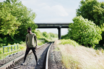 Cool black african american man walking and posing on railway in the countryside.