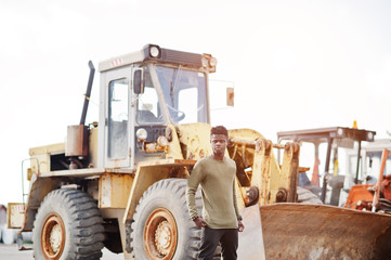 Portrait of an attractive black african american man posing next to the industrial machinery.