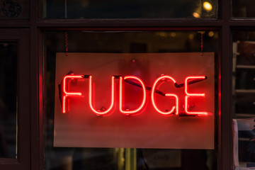 glowing red neon sign that say fudge