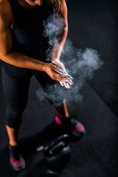 Woman athlete putting weightlifting chalk © Microgen