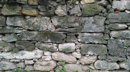 Old masonry of irregularly shaped green mossy stones. Aged weathered stonework_3