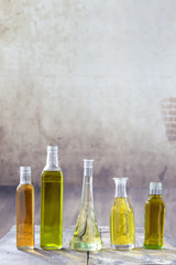 Various types of oil in bottles in a vintage wooden background