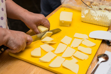 woman hands slices cheese to make an Italian pizza, process of preparing pizza. Cooking time, cooking concept, selective focus