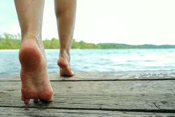 leg woman walking on the walkway wood go to the sea with sunlight