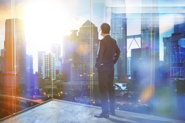 Fototapeta premium Young businessman looking out the city in the office . morning scene. .