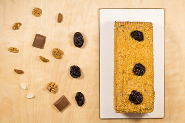 Delicious prune cake divided with nuts on wooden background