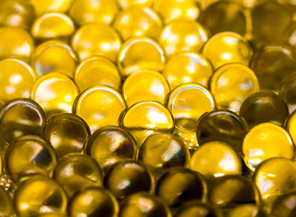 Gold shiny water gel balls. Macro photo, can be used both for advertising or cosmetics, jewellery and for medicine. Abstract background.