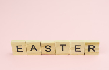 Text wooden blocks spelling the word easter on pink background