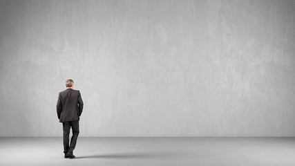 Obraz premium Business Mann vor Wand aus Beton