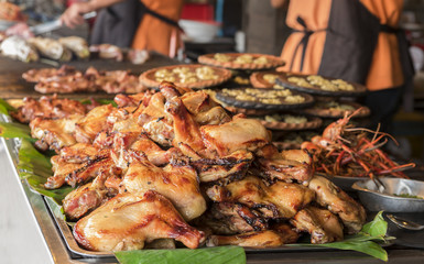 Grilled chicken roast on a tray with banana leaves in the restaurant. Close up view.