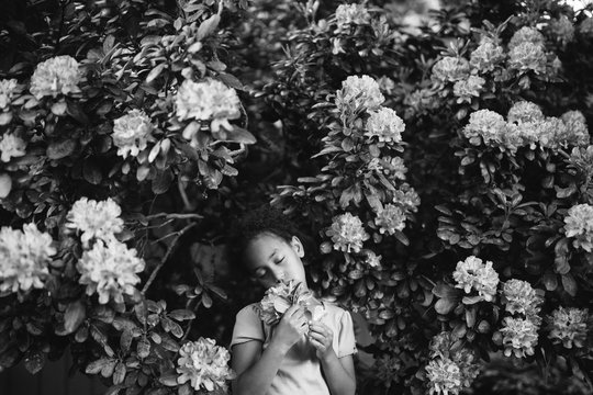 A Girl Smelling Flowers In Garden