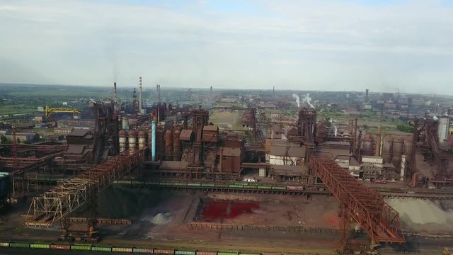 Aerial view over industrialized city with air atmosphere and river water pollution from metallurgical plant near sea. Dirty smoke and smog from pipes of steel factory and blast furnaces. Ecological
