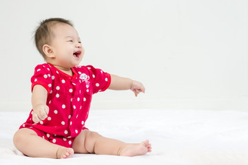 Portrait of a little adorable infant baby girl sitting on the bed and looking to the right side with copyspace