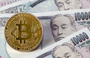 Golden Bitcoin on Japanese Yen banknote background.