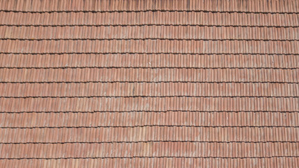Vista aerea di un tetto formato da tegole rosse ordinate ma anche rovinate dal tempo.