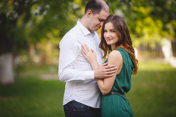 Fototapeta premium Couple in love: young girl in a long green dress and balding man in the garden. Spring or summer love story