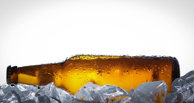 Lying bottle of beer on ice cubes. Close up. White background