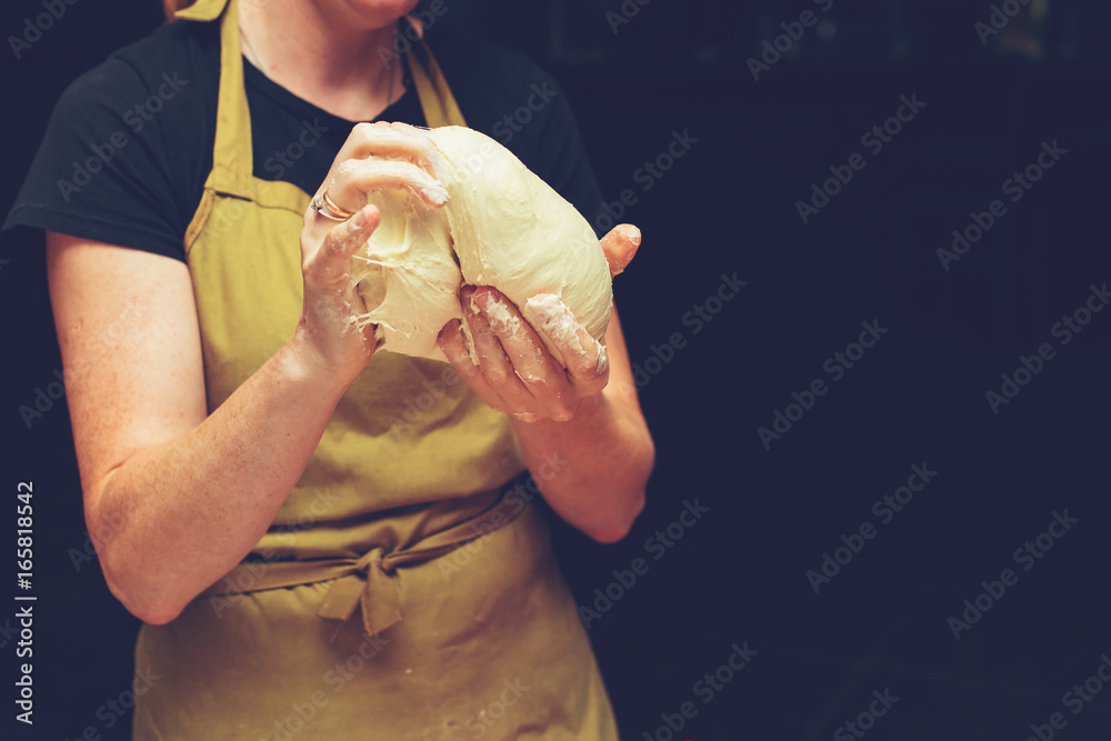 Wall mural female chef kneading dough for pizza, process of preparing pizza. Cooking time, cooking concept, toned image