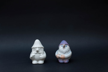 Porcelain dwarf figurines on black background