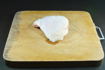 raw chicken thigh prepare to cook on wooden chop block